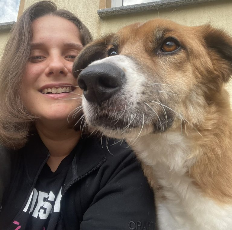 Junge Frau mit lässigem Outfit lächelt in einem Zugabteil.